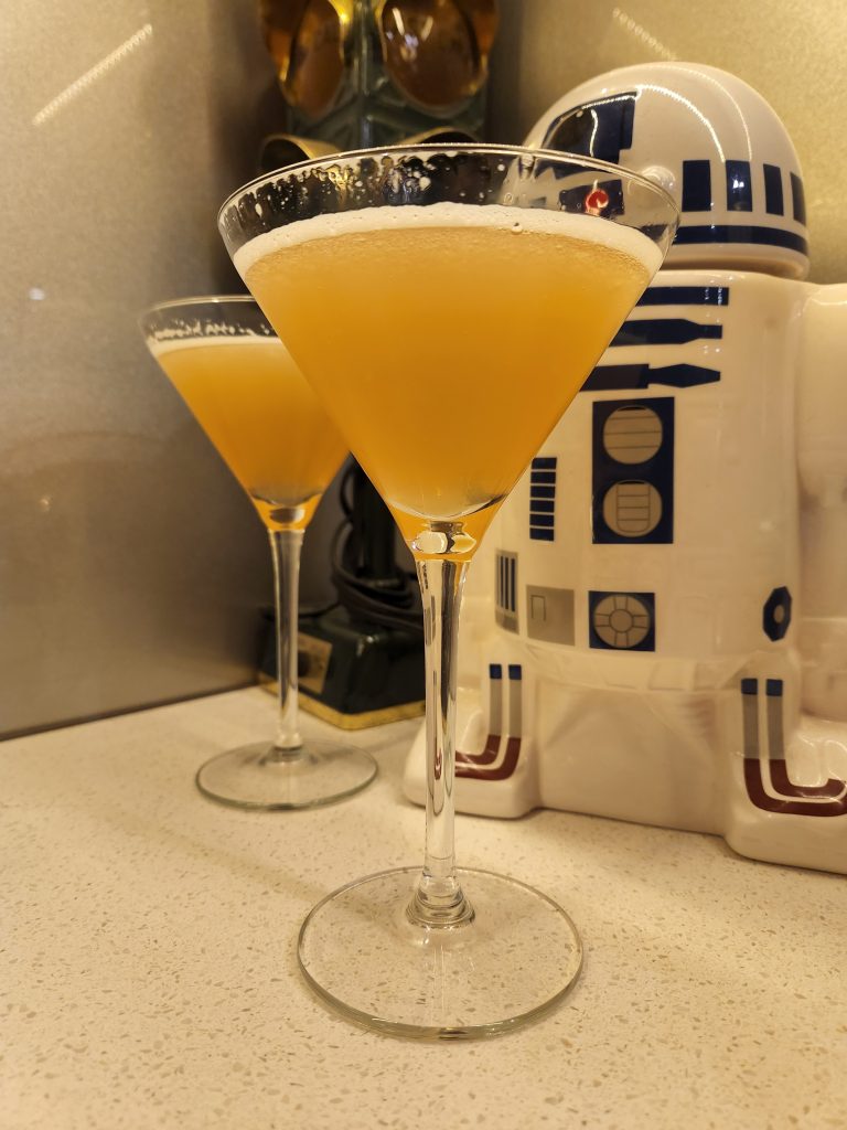 Two Yaka Hula Hickey Dula cocktails in Martini glasses in front of a ceramic R2D2.
