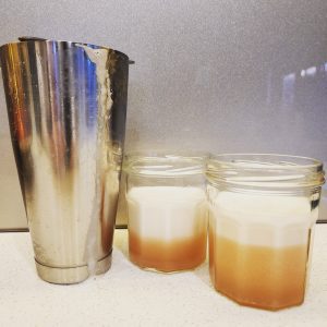 Two Tequila Sours in jam jars next to a cocktail shaker.