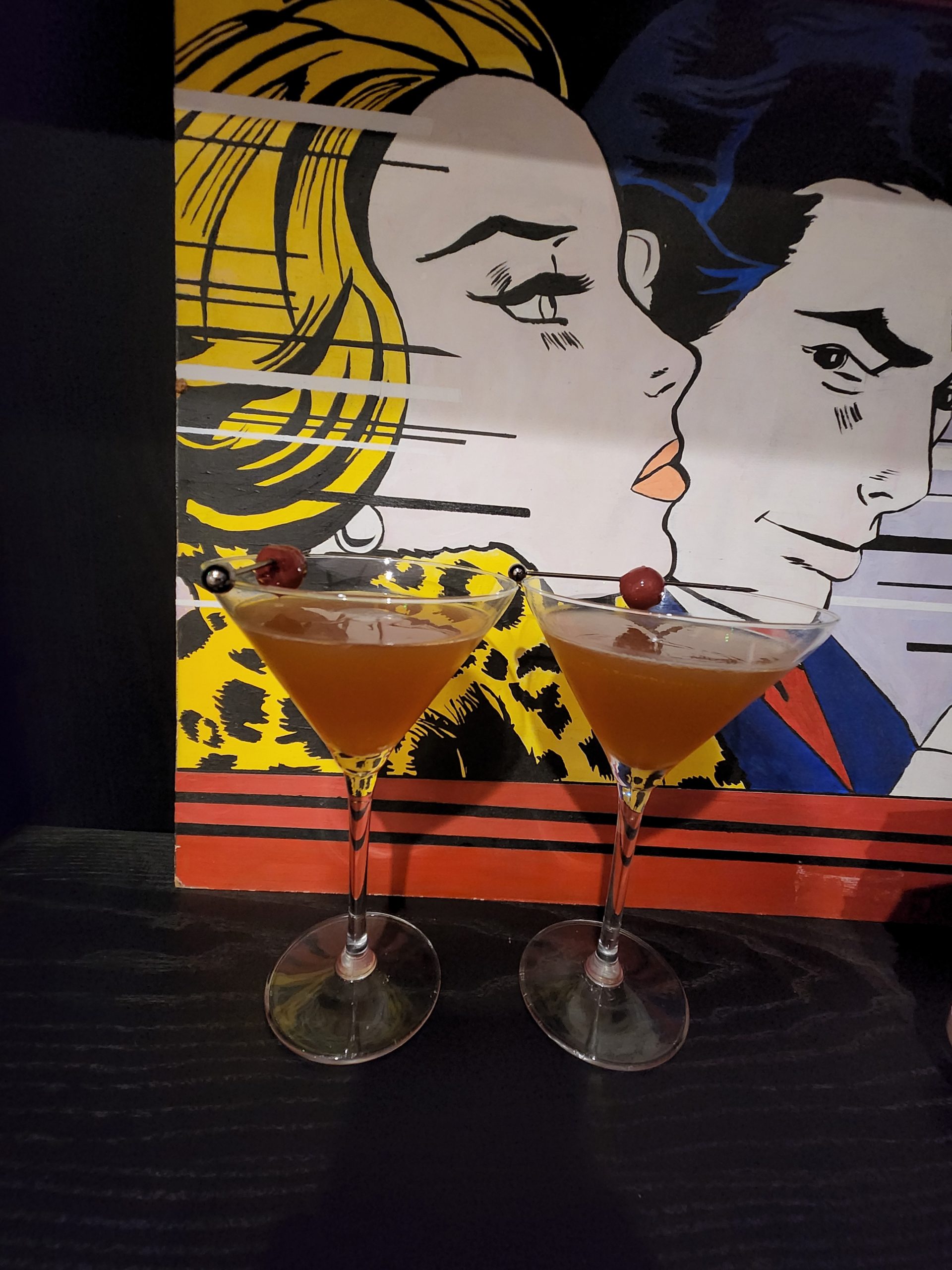 Two Bella Donna Daiquiris in front of a painting.