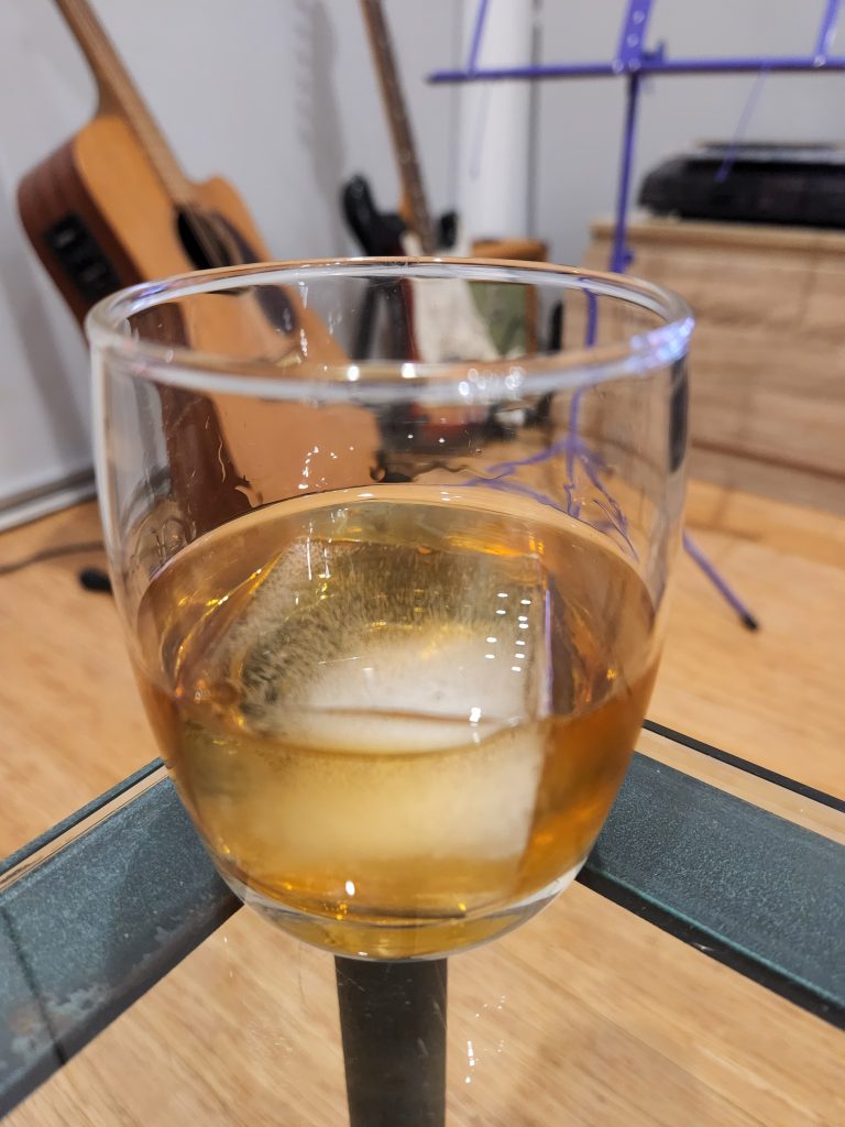 A Godfather cocktail on a table in front of guitars.