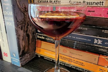 A Blood and Sand cocktail on a bookshelf.