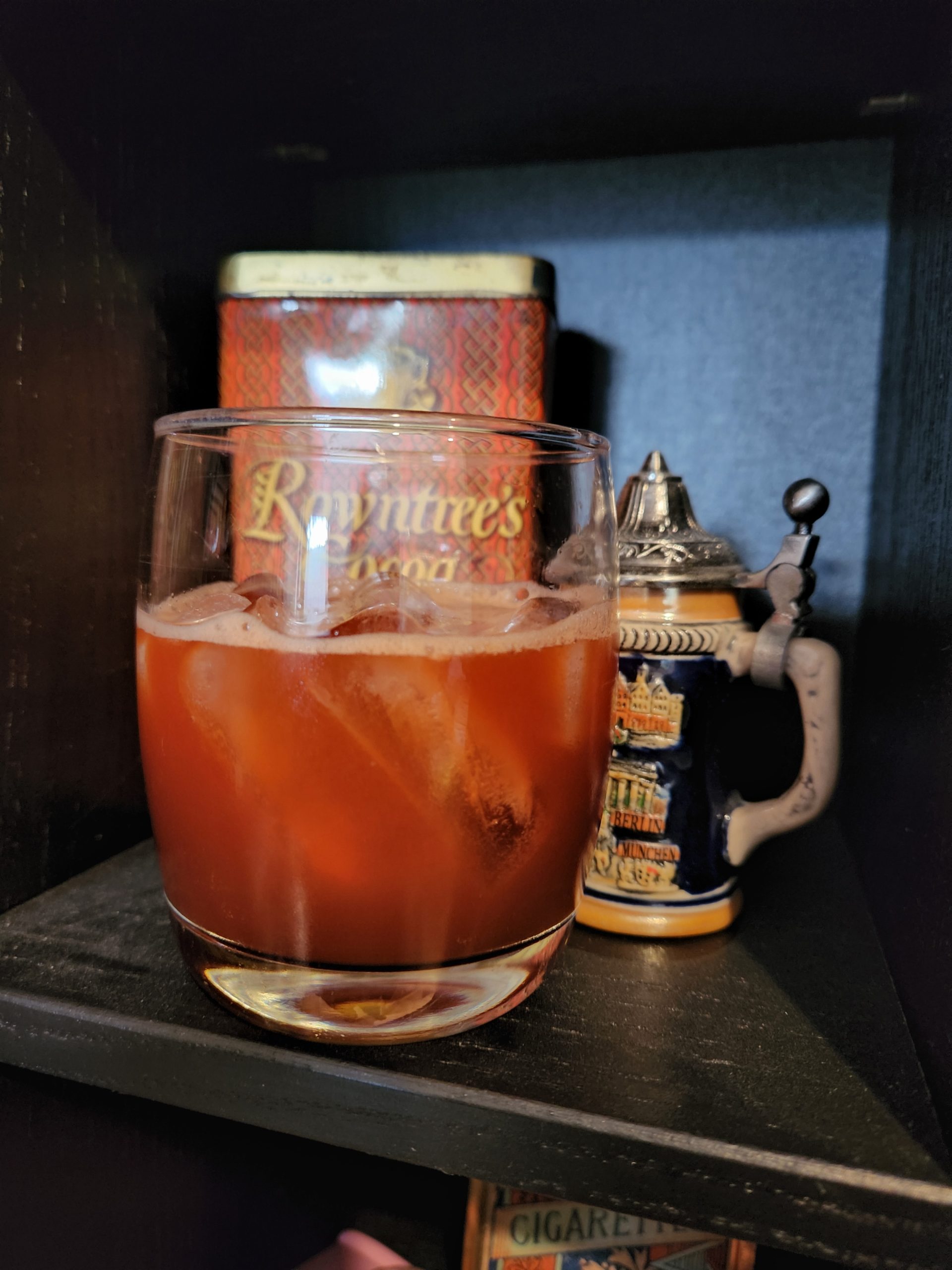 California Surfer cocktail on a bookshelf in front of a mini German beer stein.