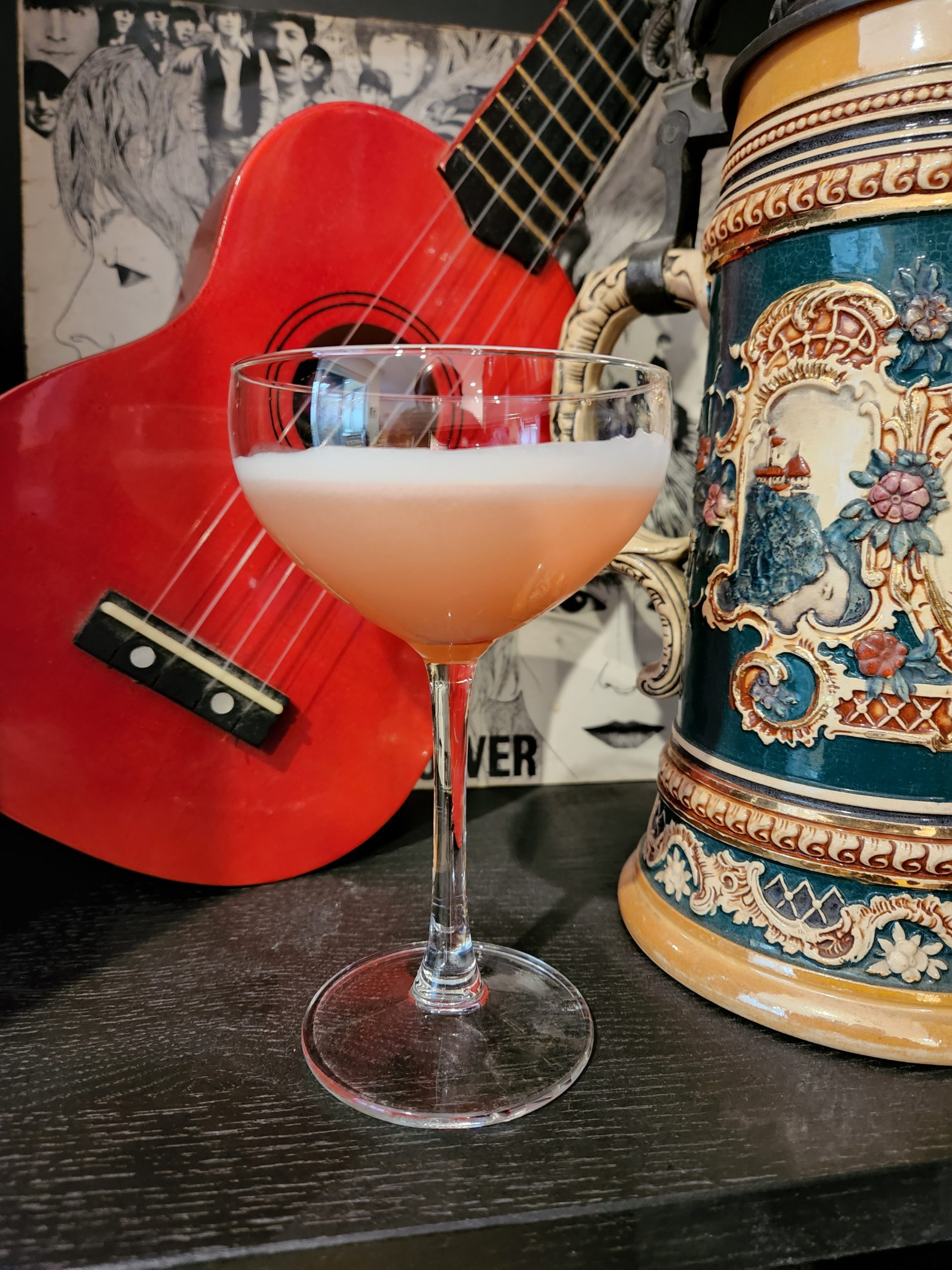 A Commodore Cocktail in a coupe glass sitting in front of a ukulele.
