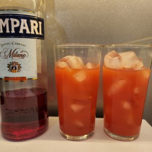 Two Garibaldi cocktails next to a bottle of Campari.