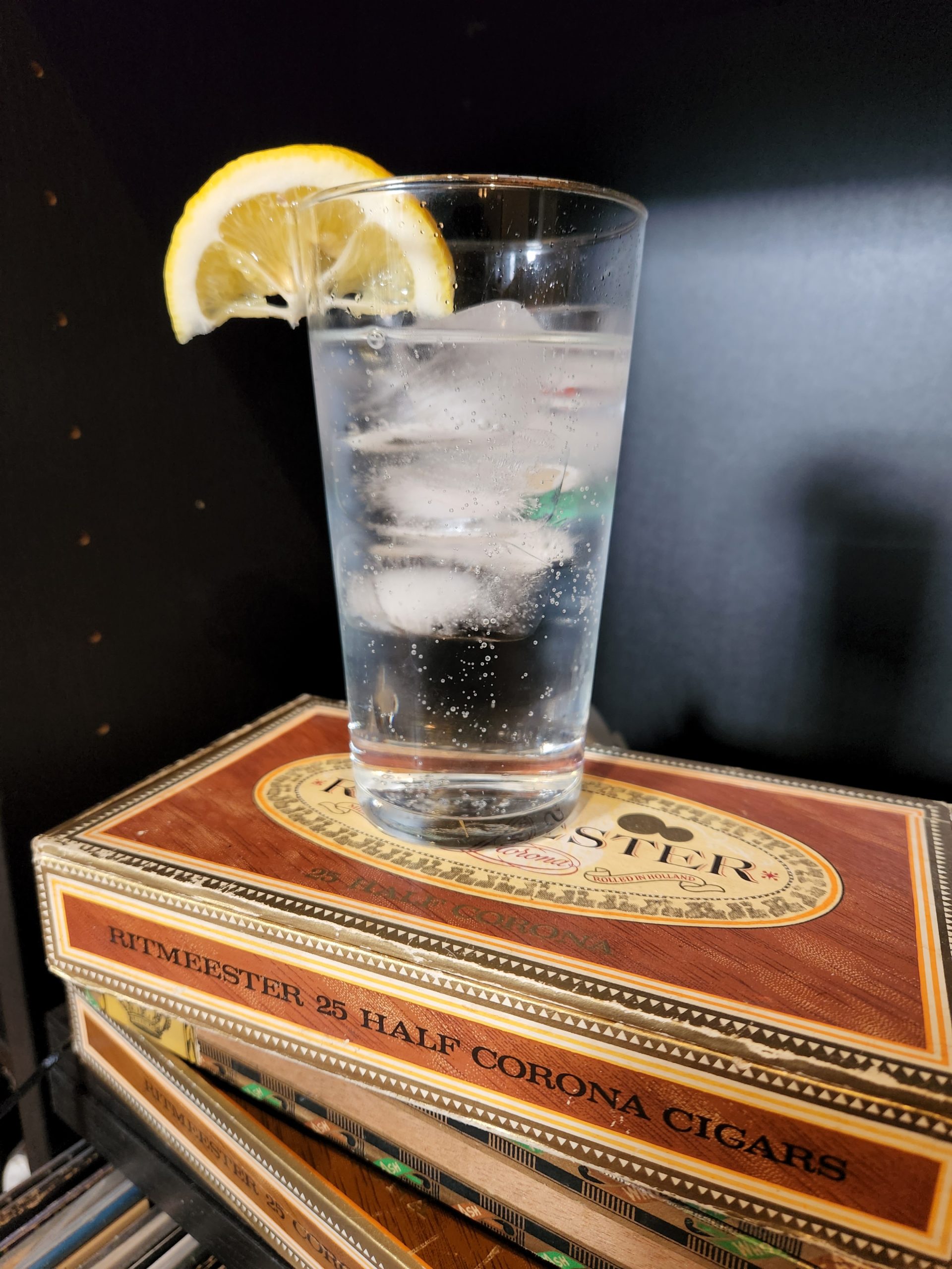 A Gin and Tonic sitting on cigar boxes.