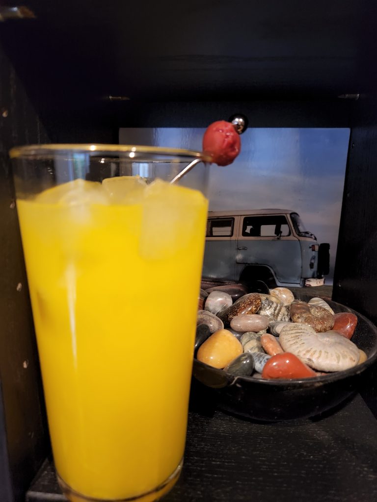 A Harvey Wallbanger cocktail in front of a bowl of rocks.