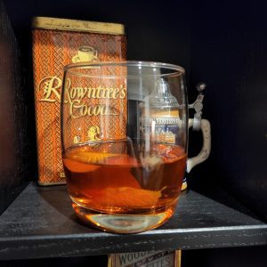 A Sazerac cocktail on a bookshelf.