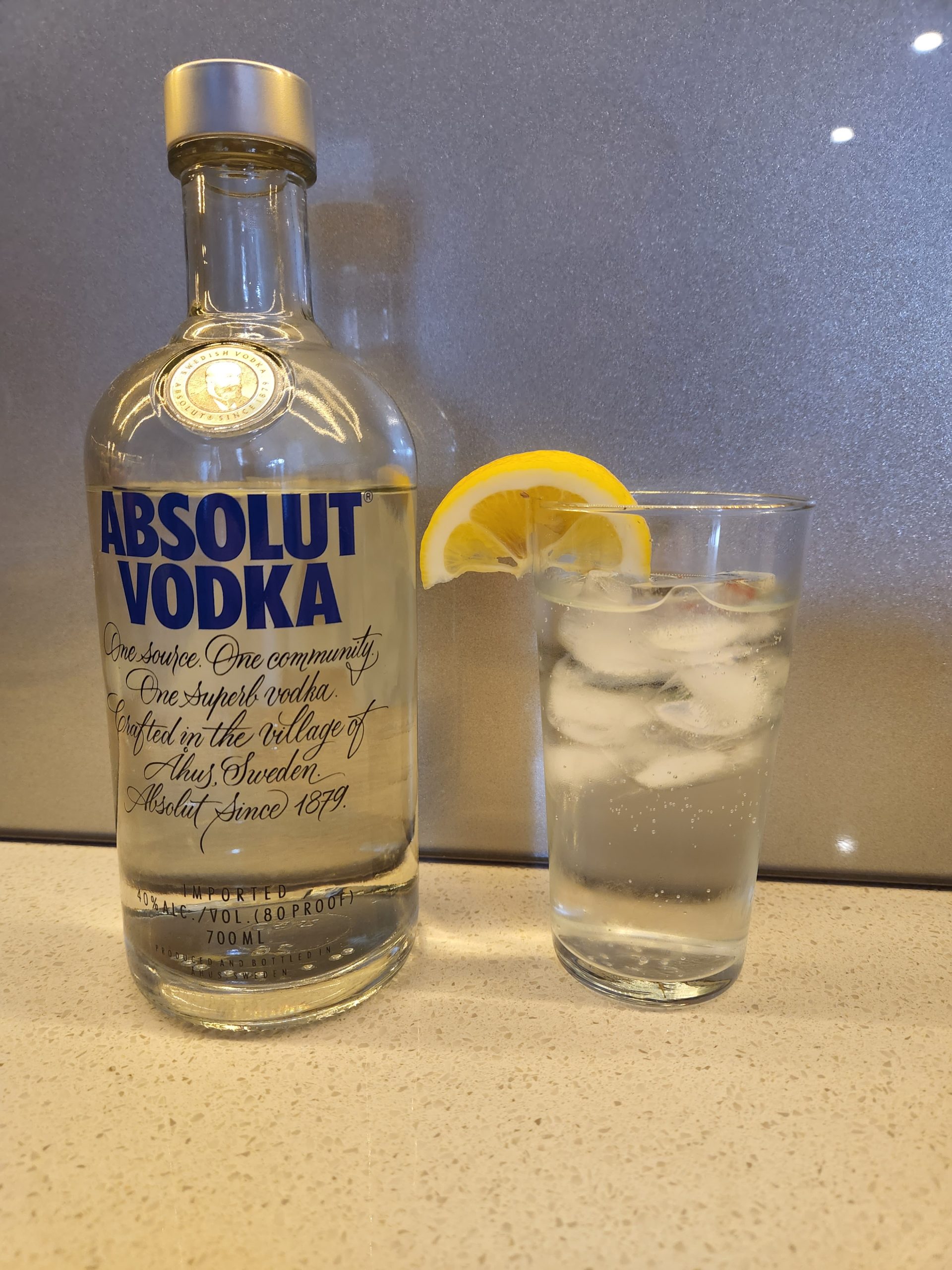 A Vodka Tonic next to a bottle of vodka.
