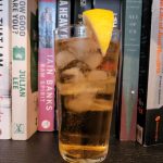 A Whiskey Ginger cocktail on a bookshelf.