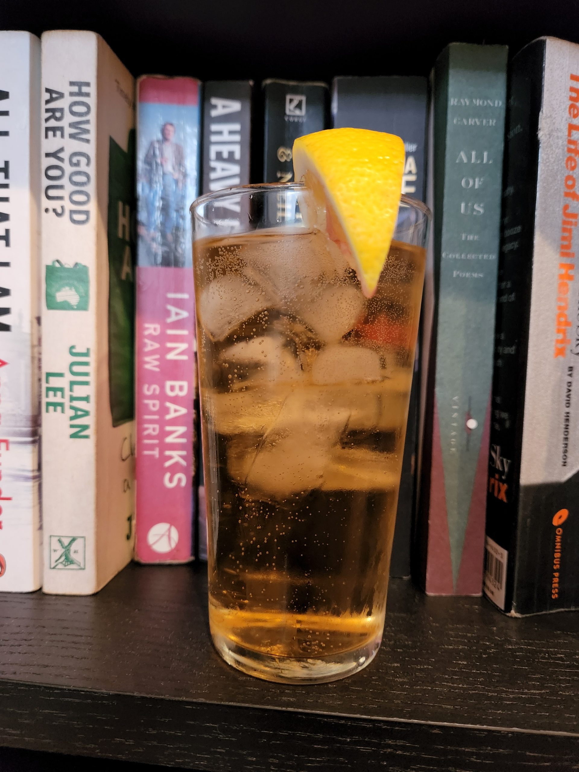 A Whiskey Ginger cocktail on a bookshelf.