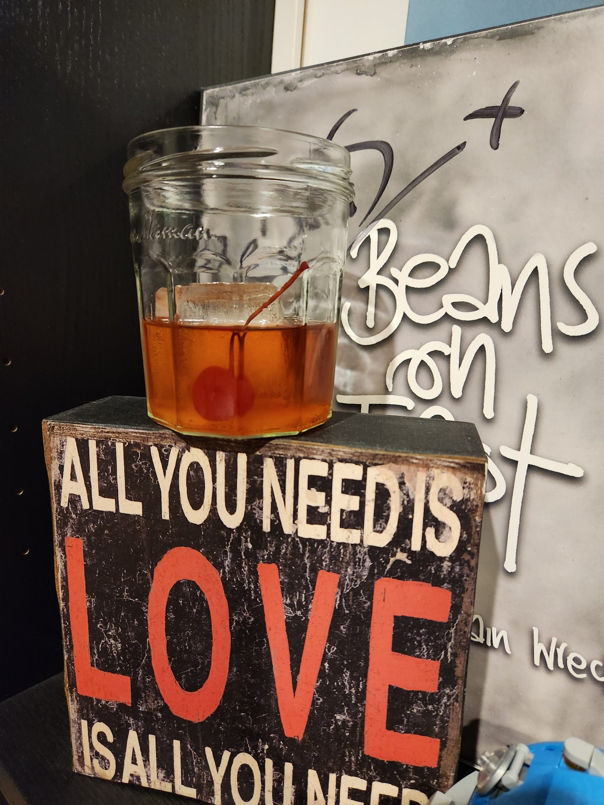 An Old Fashioned cocktail on a bookshelf sitting in front of a record.