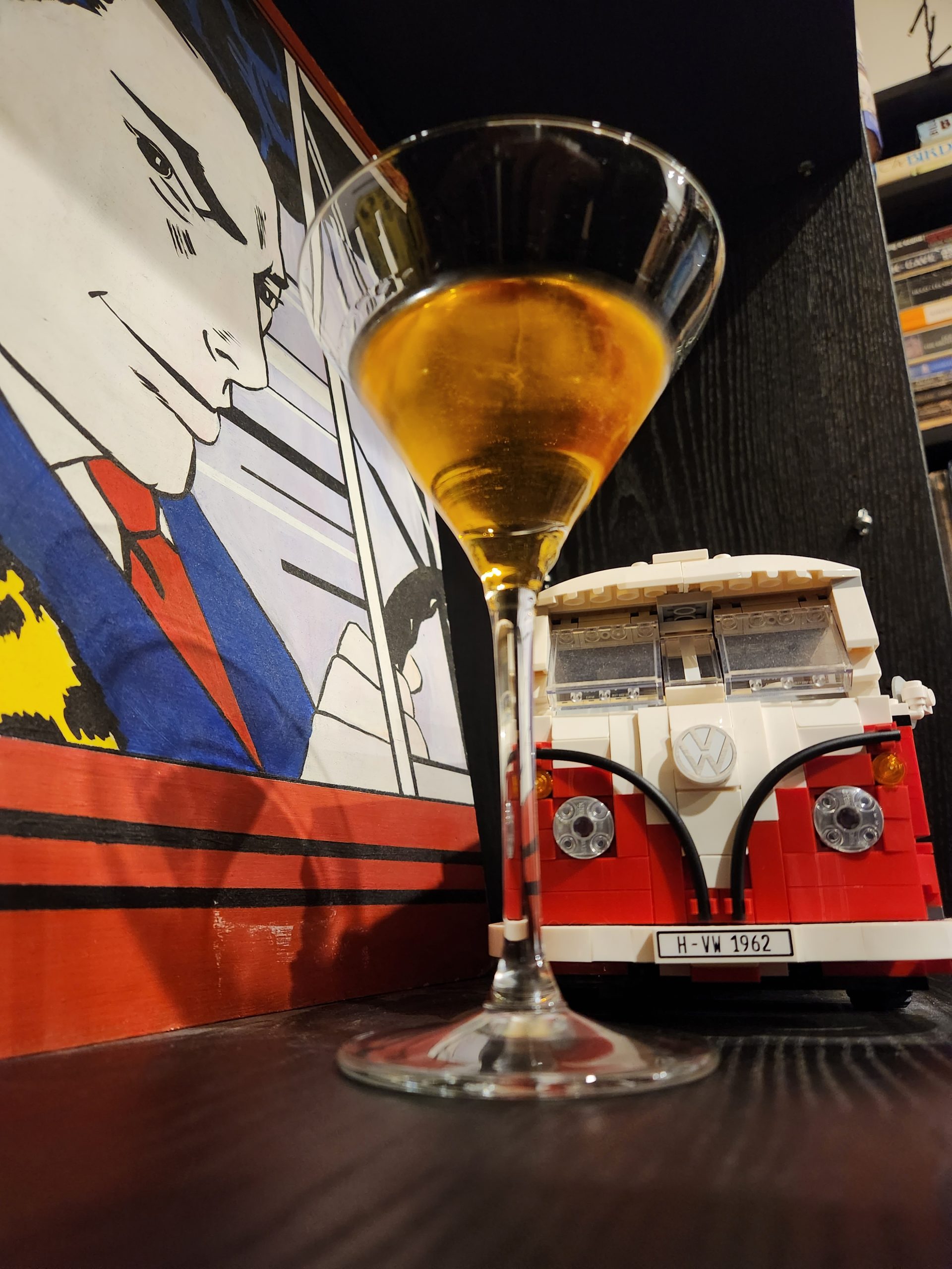 A Guadalajara Cocktail in a Martini glass on a bookcase with a Lego VW van behind it.