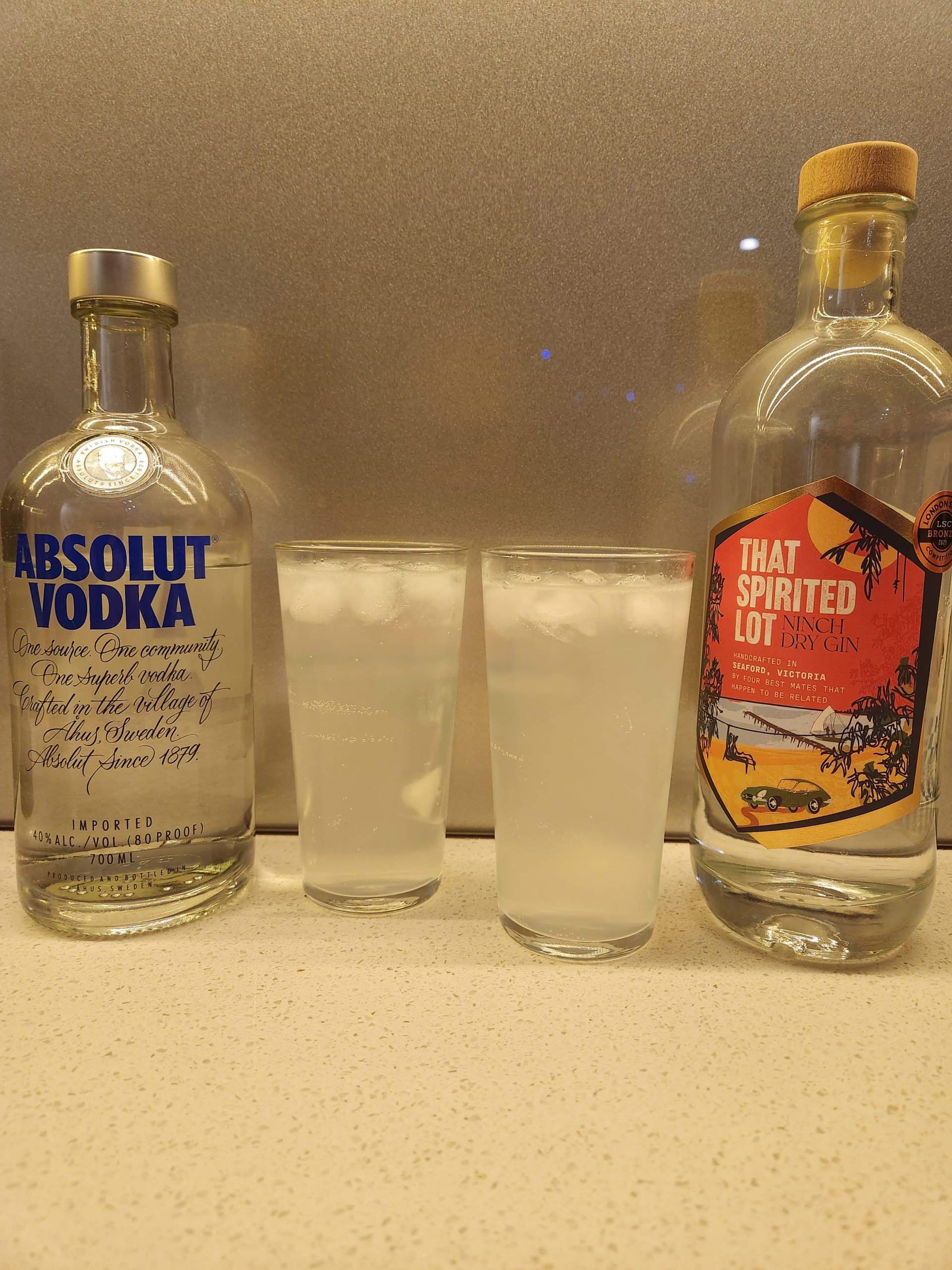 Two glasses of Kansas City Ice Water with a bottle of vodka and a bottle of gin.