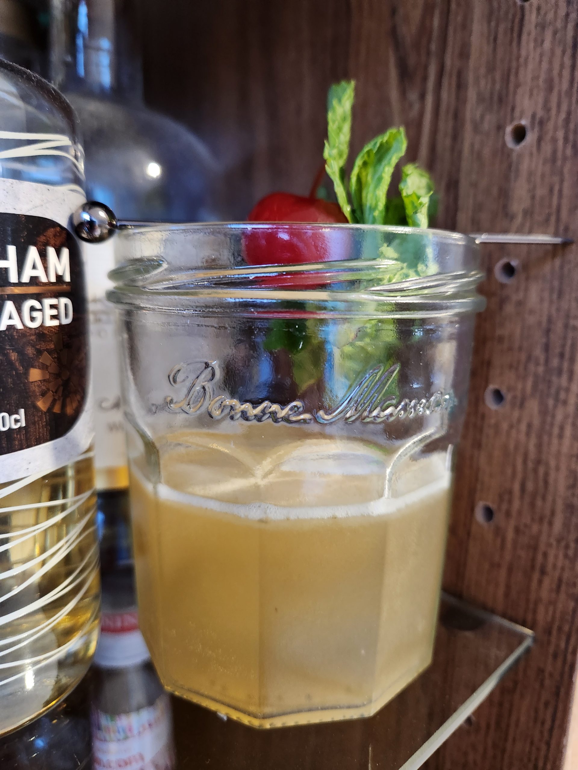 Test Pilot cocktail served in a jam jar sitting on a shelf.